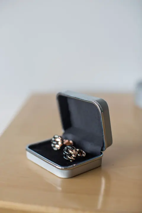 A pair of knot cufflinks resting in an open metal case