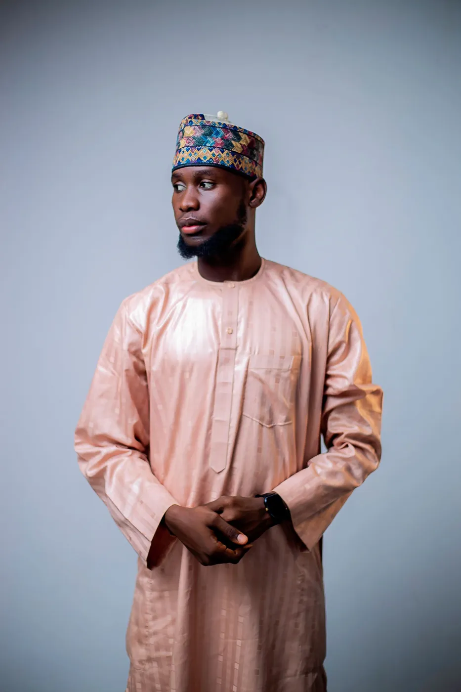 A man in a long dusty rose kaftan with tonal embroidery